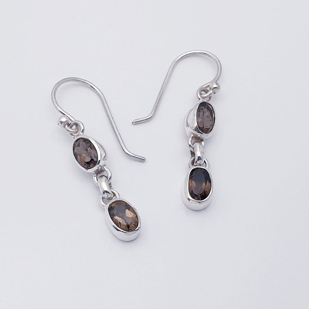 A pair of dainty smoky quartz and sterling silver earrings flat lay