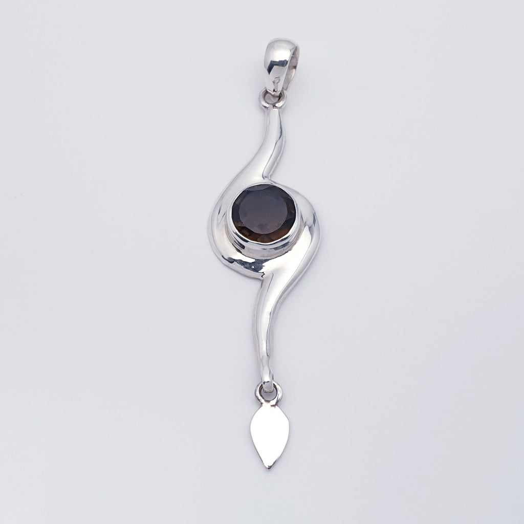 A pendant with a smoky quartz gemstone set in a contemporary style sterling silver design flat lay