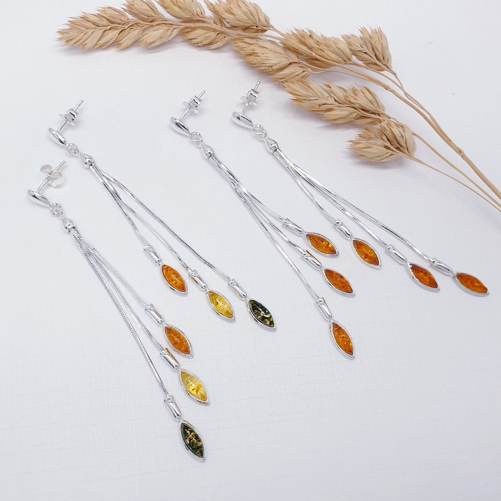 Two pairs of Toffee and Mixed Amber Sterling Silver Long Cascading Stud Drop Earrings flat layed with dried foliage