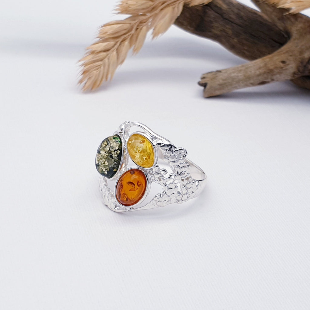 Our mixed amber floral ring is displayed on a white background with wood and foliage decorations