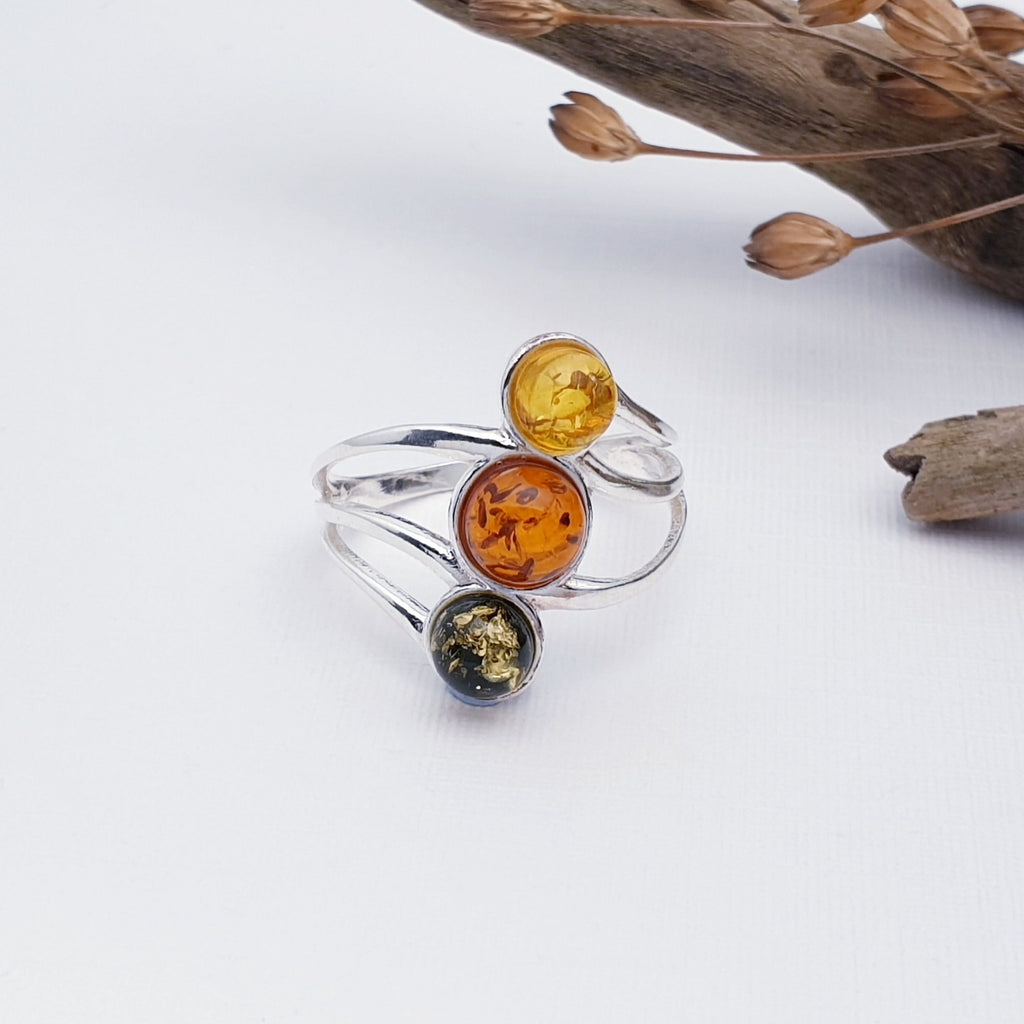 Our Mixed Amber Orbit ring displayed against a white background with wood and autumn foliage as decorations