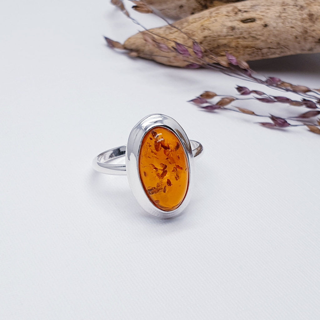 Our Toffee Amber Simple Oval ring displayed on a white background with wood and autumn foliage as decorations