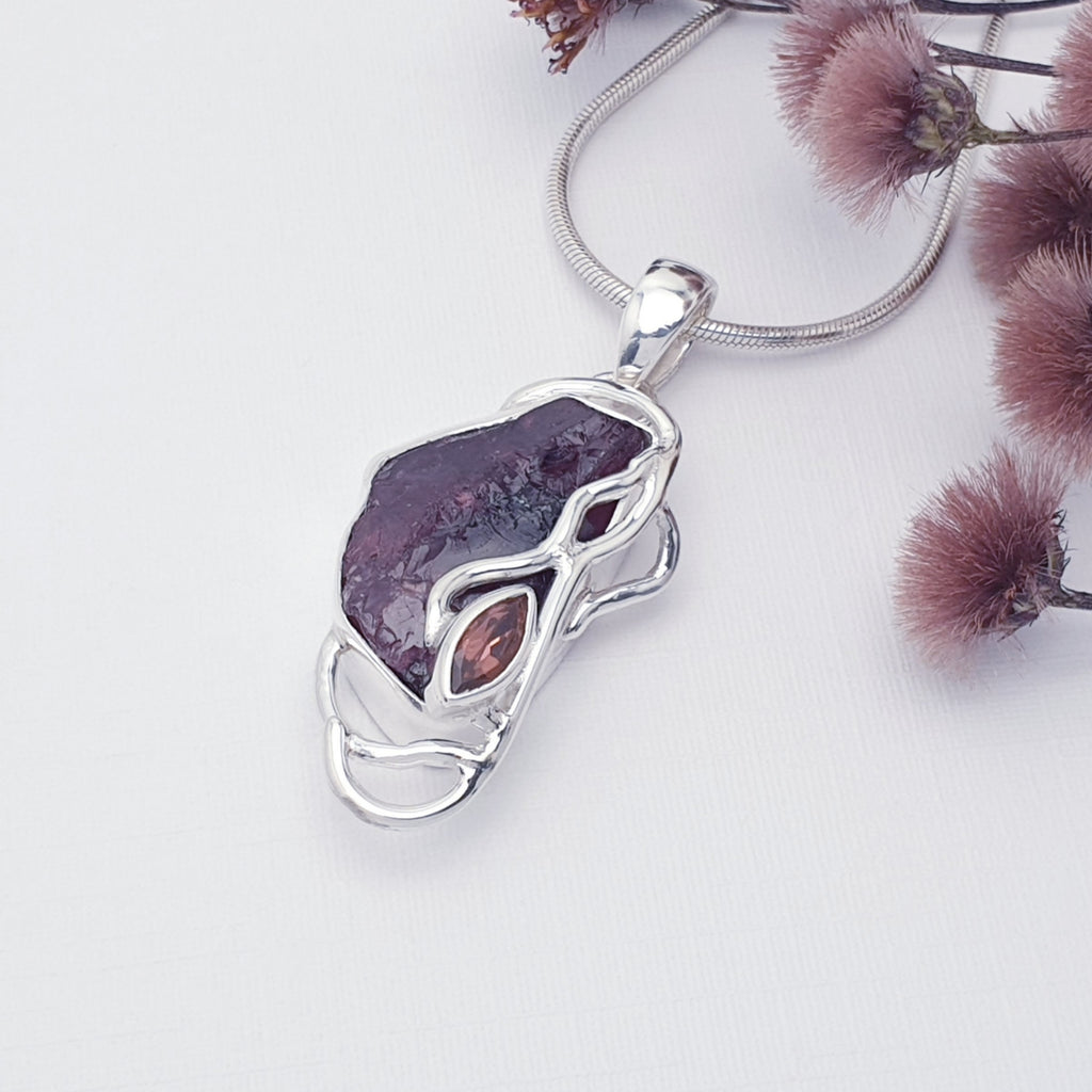 Raw garnet pendant with sterling silver vine design, displayed on a white background