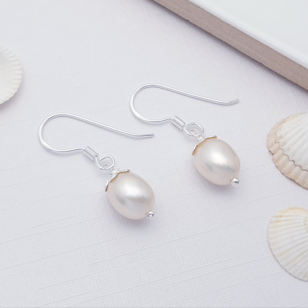 Handmade pearl and sterling silver earrings displayed on a white background