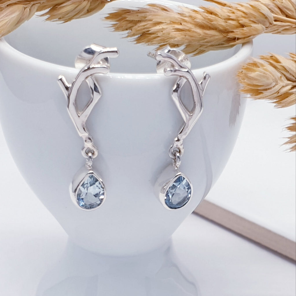 Our blue topaz vine earrings suspended from an egg cup with foliage as decoartions