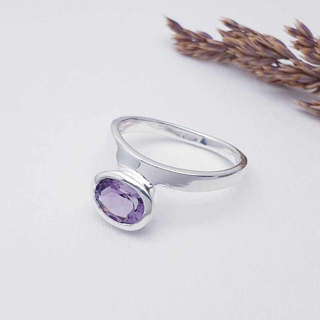 purple amethyst gemstone ring with sterling silver displayed on a white background with autumn foliage as decoration
