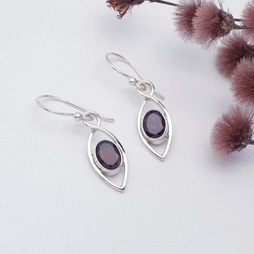 Garnet Sterling Silver Raindrop Earrings on a white background with red foliage 