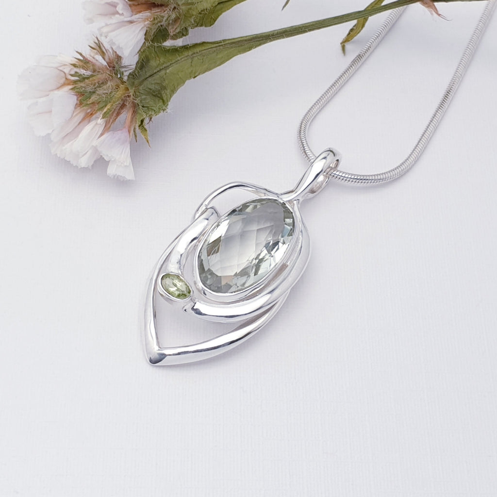 Green amethyst and peridot pendent on a white back ground with foliage