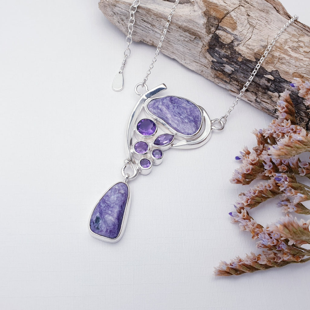 Amethyst and Charoite necklace on a white background with purple and pink foliage.