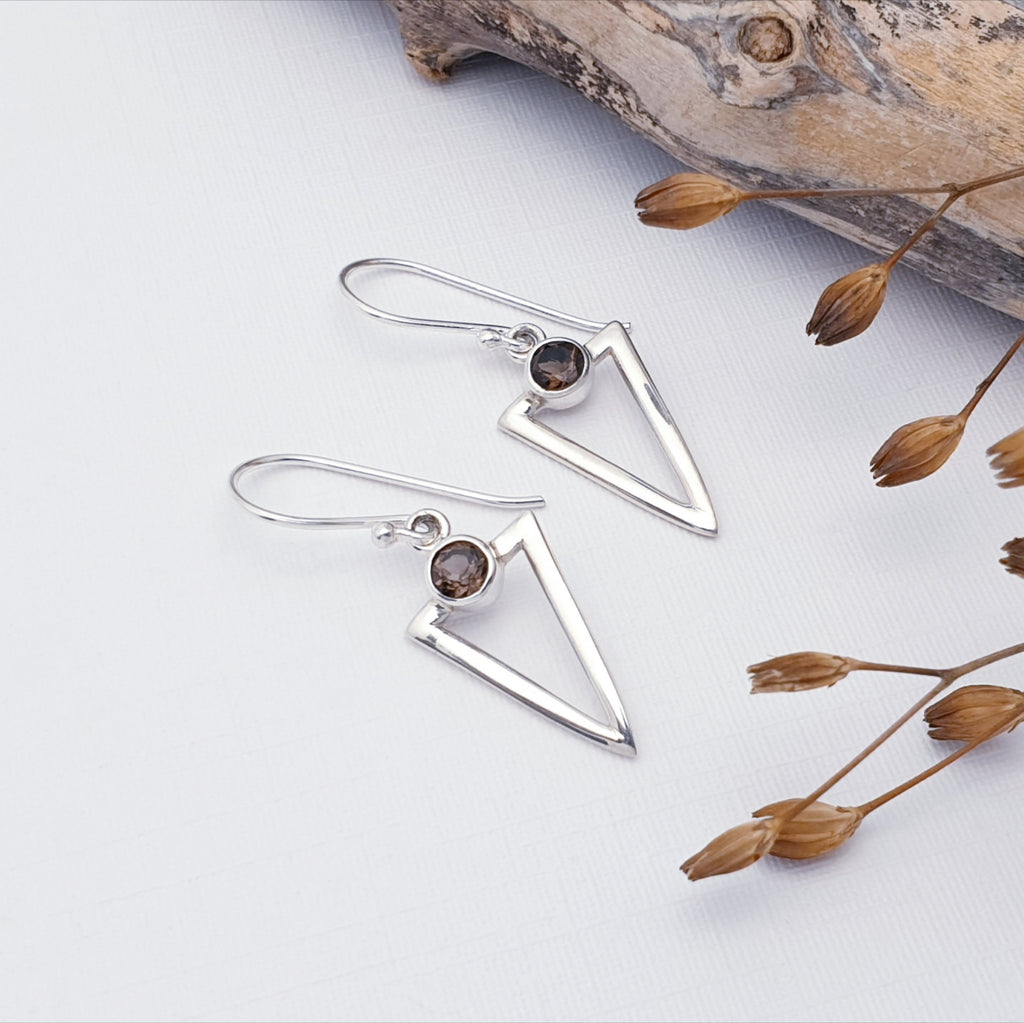 Smoky Quart Acute Triangle earrings on a white background with drift wood and brown filigree on the right hand side