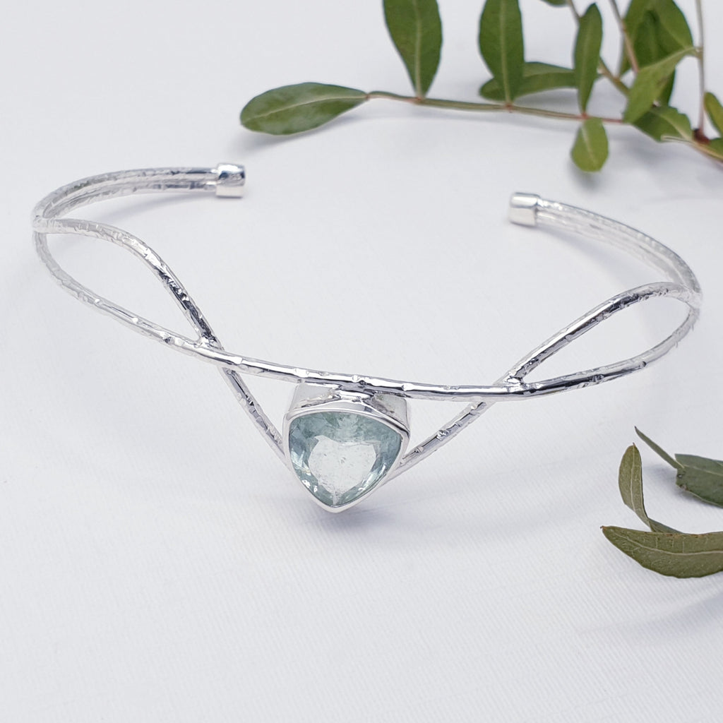 Our Aquamarine sterling silver galatea cuff displayed on a white background with leafy branches as decoration