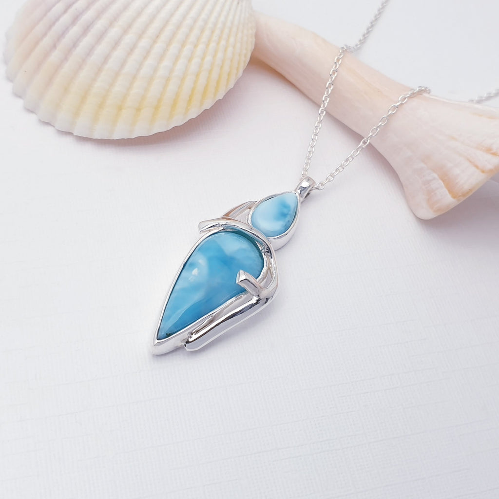 Blue pendant necklace on a white background with seashells.
