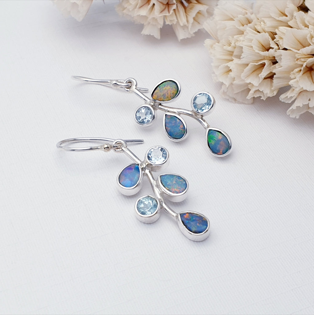 Our Opal and blue topaz summer berry earrings pictured against white with white flowers in the background as decoration