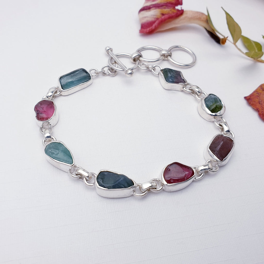 Our mixed tourmaline multistone bracelet pictured against white with dried flowers and leaves in the background as decorations