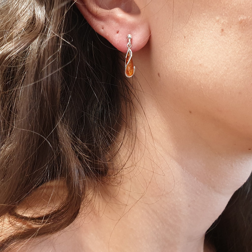 A model wearing  a teardrop amber and sterling silver earring.