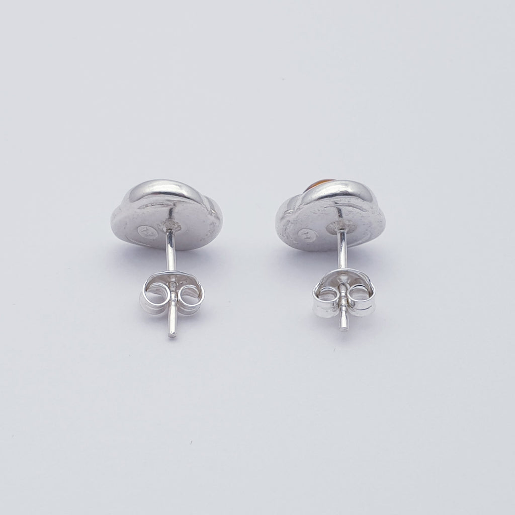 A pair of amber and sterling silver stud earrings side view.
