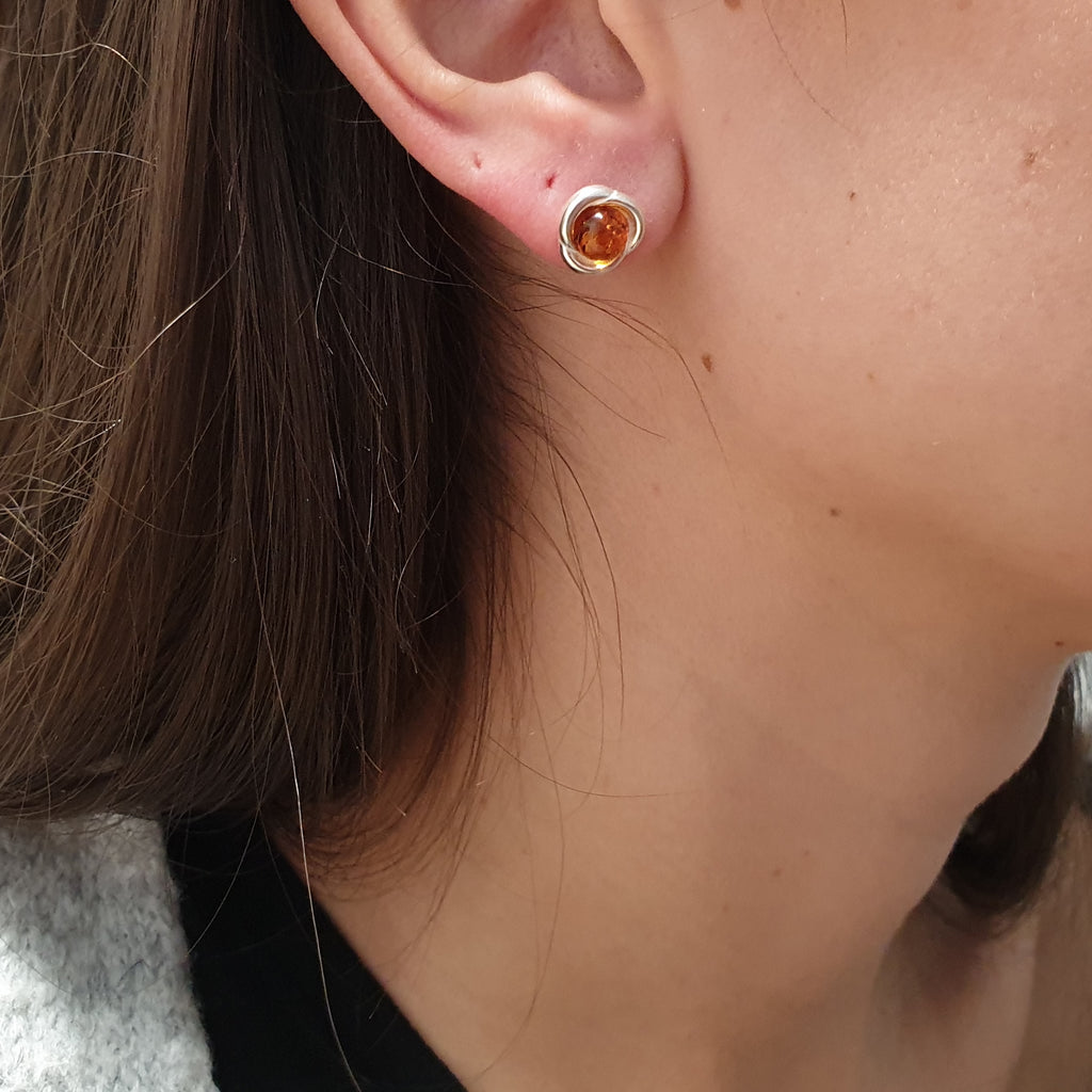A model wearing an amber and sterling silver stud earring.
