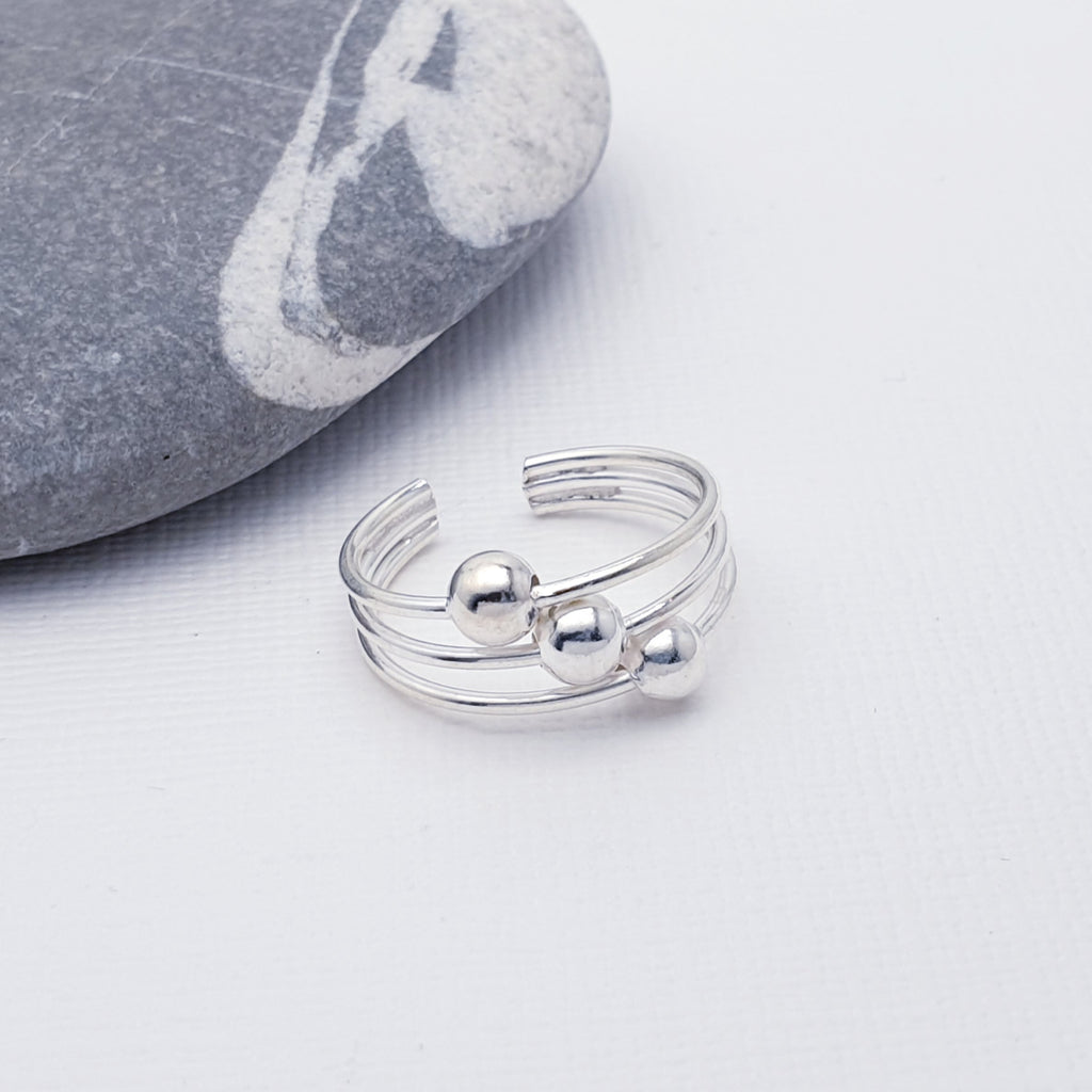 This simple design features three silver bands which are fused together at both ends. Three static silver balls decorate the middle bar creating a fun and interesting design. Open at the back, this toe ring is adjustable.