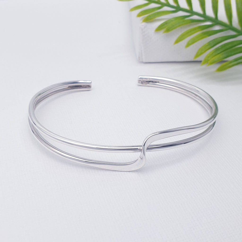 This bangle features two bands which criss cross over each other adding a contemporary touch. Adjustable to most wrist sizes, this bracelet is light and easy to wear and is perfect as a gift for a loved one or as a little treat for yourself.