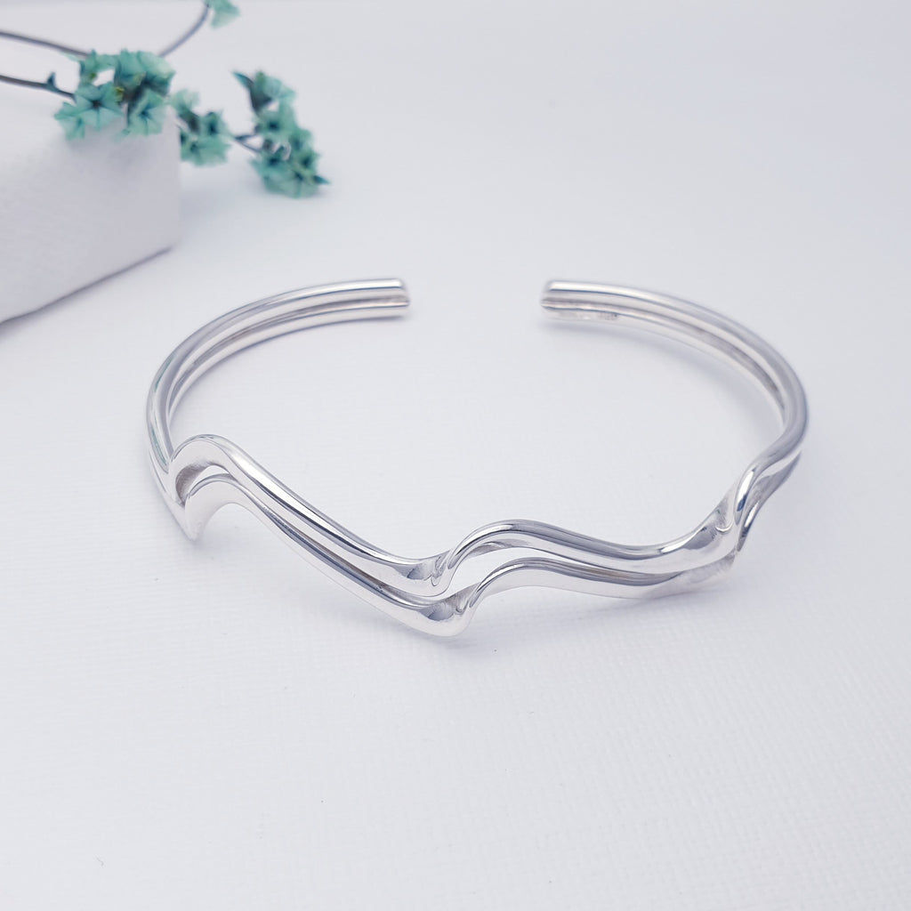 This bangle features two bands, shaped in a ripple effect that is inspired by the movement of waves. Something a little different, this cuff is sure to be well received. Adjustable to most wrist sizes, this bracelet is light and easy to wear and is perfect as a gift for a loved one or as a little treat for yourself.