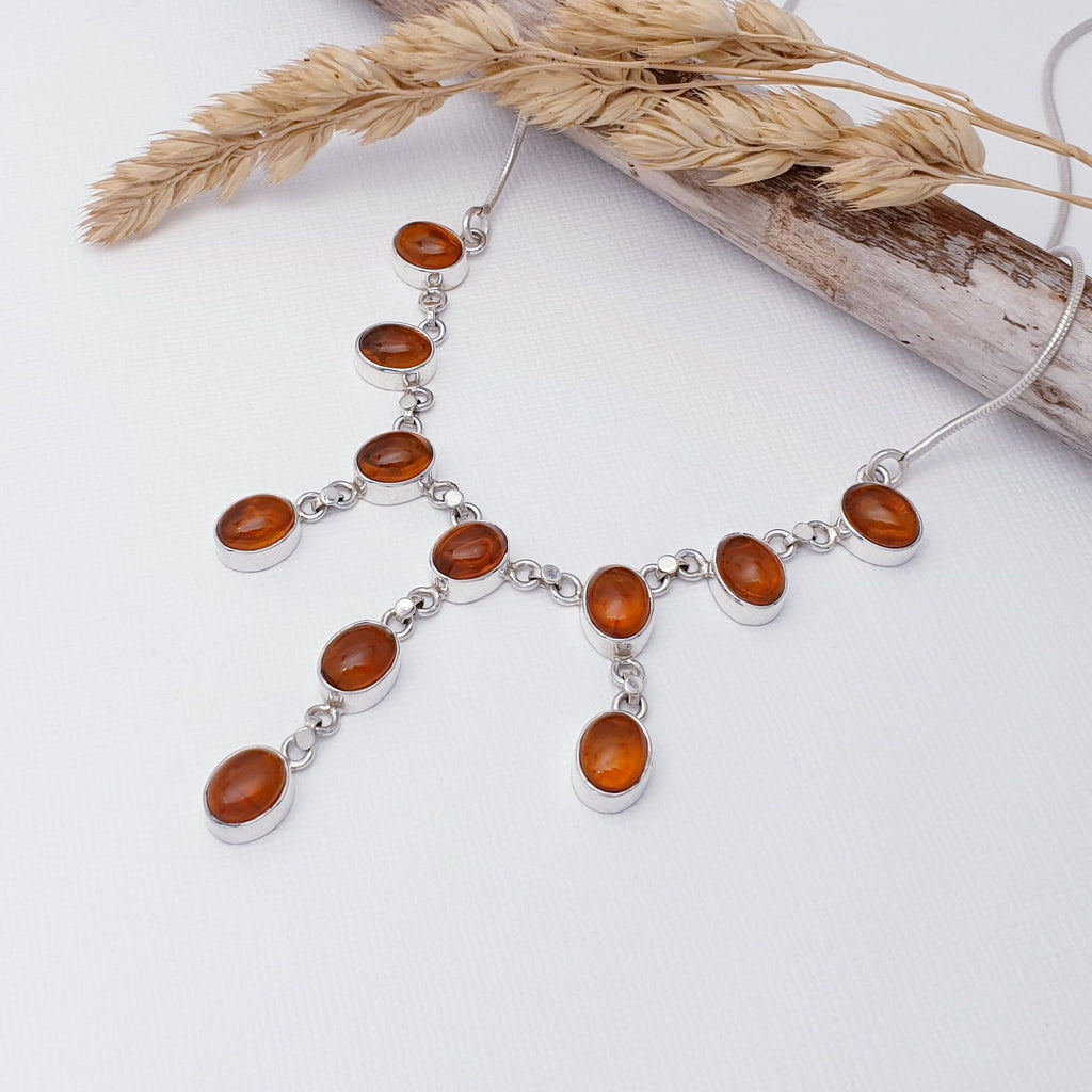 Our Amber Sterling Silver Staggered Necklace is perfect for every day wear or special occasions.  This necklace features eleven toffee, Baltic Amber oval stones, all in simple Sterling Silver settings. These hang in a staggered formation, starting with single Amber stones either side to three in a row in the middle.