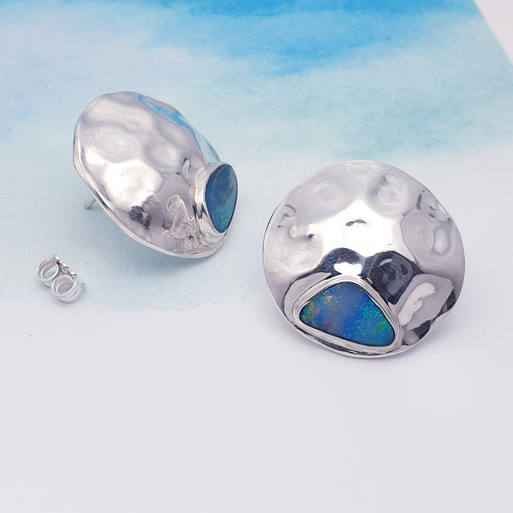 Each earring compromises of a beautiful Australian Opal doublet set in Sterling Silver. Our Silversmiths have showcased the gorgeous stone with a hammered textured Sterling Silver disc shape. These statement studs are perfect for adding a little sparkle to any outfit or occasion.