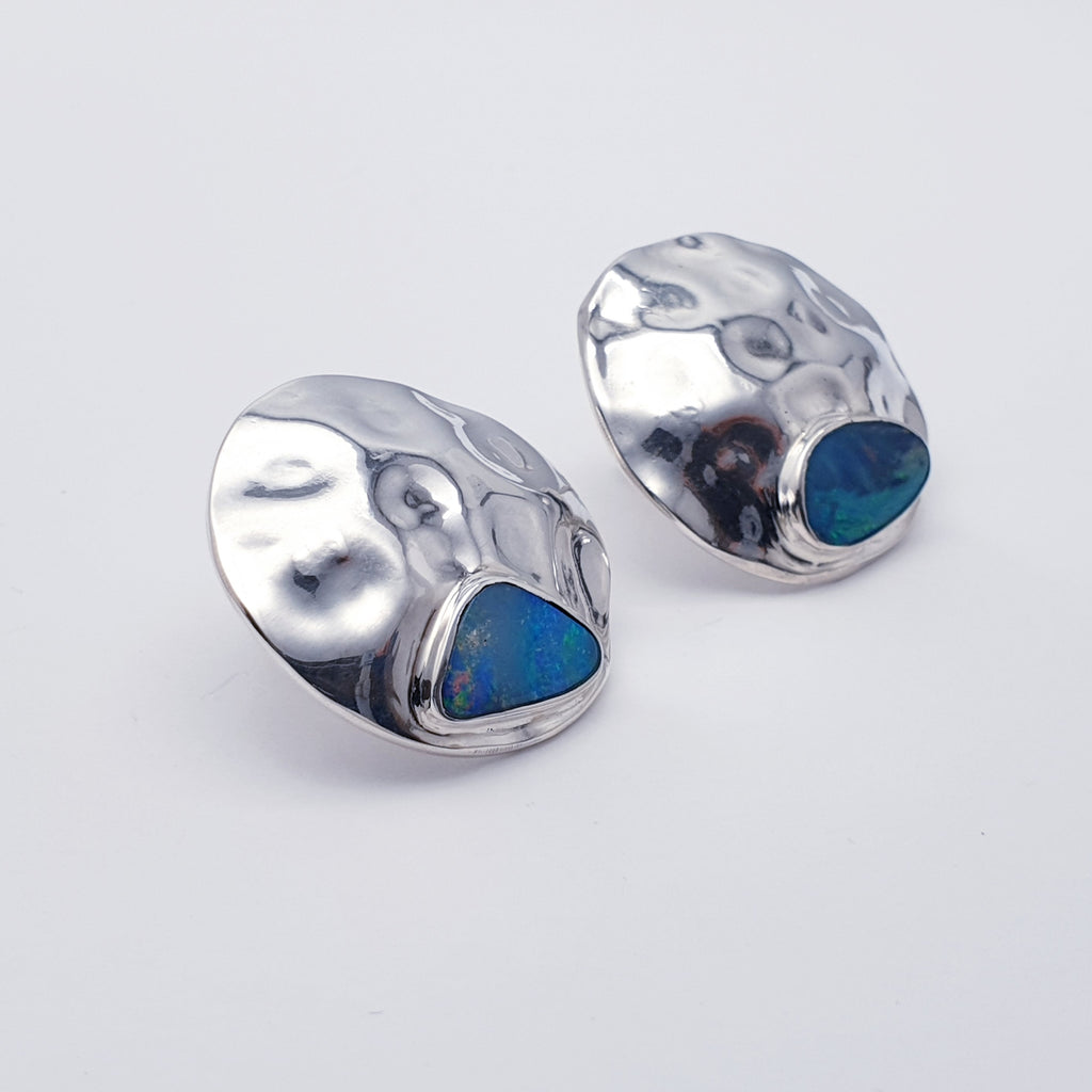 Each earring compromises of a beautiful Australian Opal doublet set in Sterling Silver. Our Silversmiths have showcased the gorgeous stone with a hammered textured Sterling Silver disc shape. These statement studs are perfect for adding a little sparkle to any outfit or occasion.