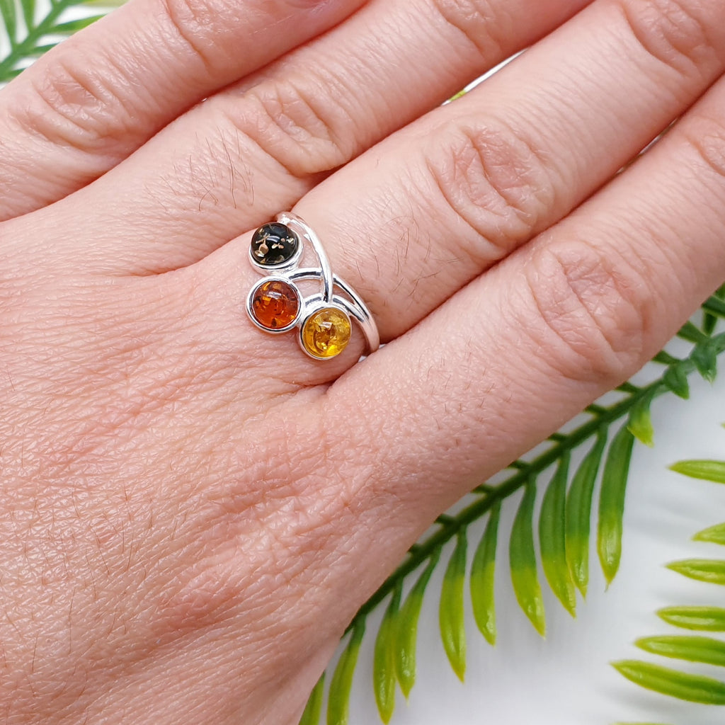 This ring features three Mixed Amber stones; one green, one Toffee and one yellow in simple settings. Celtic inspired design decorating the top and bottom of the ring in Sterling Silver. 