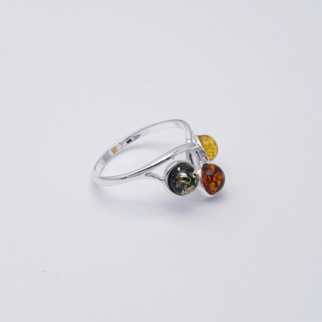 This ring features three Mixed Amber stones; one green, one Toffee and one yellow in simple settings. Celtic inspired design decorating the top and bottom of the ring in Sterling Silver. 