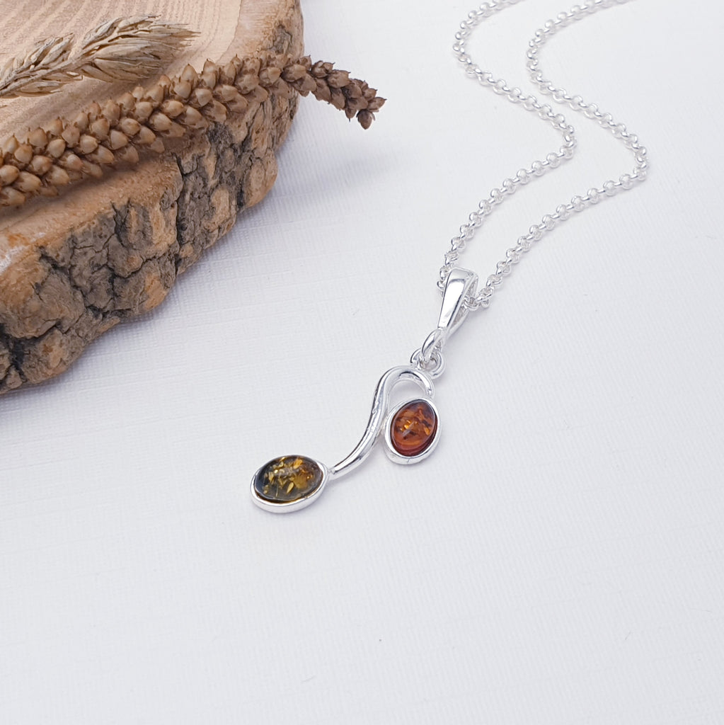 This gorgeous pendant features two oval Amber stones; one Toffee Amber stone and one green. Each stone is hanging from a Sterling Silver vine. A beautiful nature inspired design, this pendant is sure to be well received.