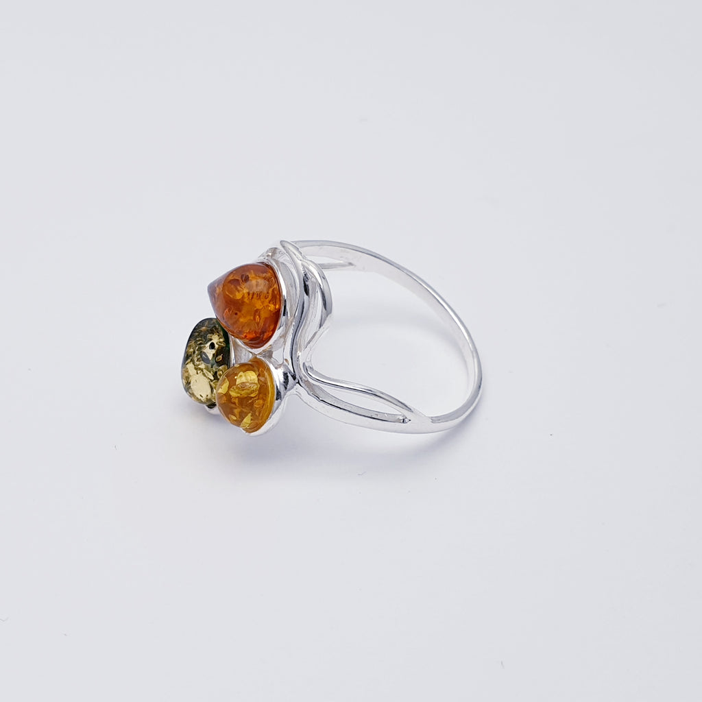 This ring features three Baltic Amber stones; two teardrop Toffee and green stones, and one round yellow Amber stone. The three Amber stones are showcased by a simple Sterling Silver wave design that decorates the top and bottom
