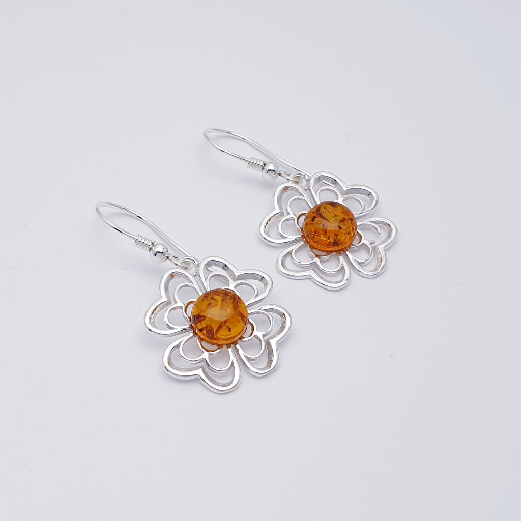Each earring features a round beautiful Toffee Amber stone. Showcasing the Amber stone is a Sterling Silver flower cut out design. The intricate flower detailing creates an unusual design, these earrings are perfect for any occasion. 