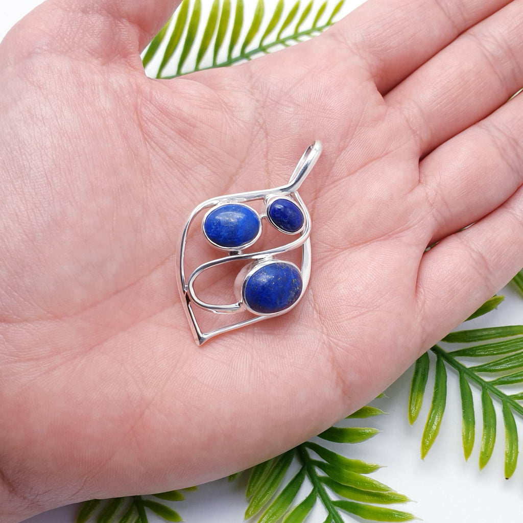 This pendant features three oval cabochon, Lapis Lazuli stones, in simple settings. Our Silversmiths have elegantly framed the stones in a ribbon of Sterling silver, in the shape of a teardrop. A beautiful swirl of silver finishes this design off perfectly.   The stones used in this pendant are gorgeous; very deep blue Lapis Lazuli with easily visible little specs of golden pyrite, just beautiful.