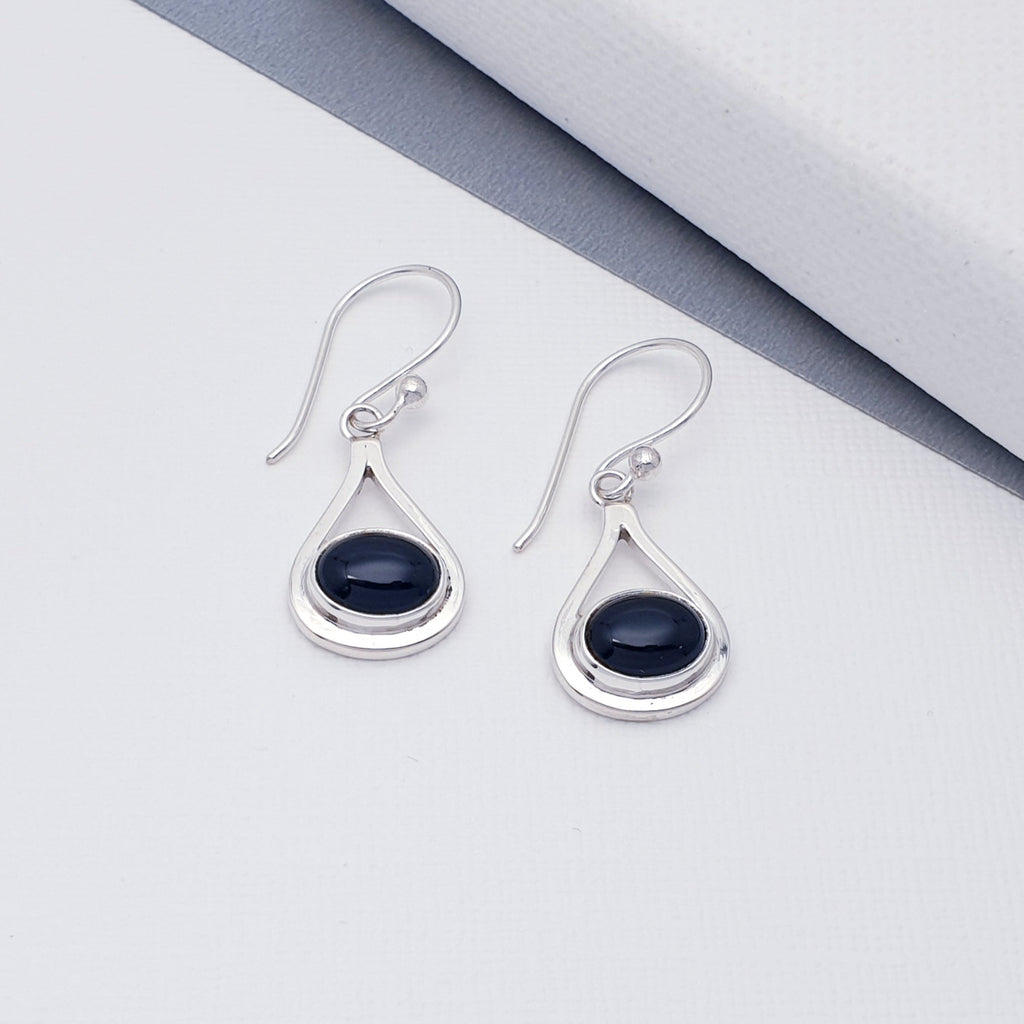 Each earring features an oval cabochon, Onyx stone in a simple setting. Around the setting is a band of Sterling Silver that flows into a teardrop shape.  A contemporary twist on a timeless design, these are bound to be very well received.