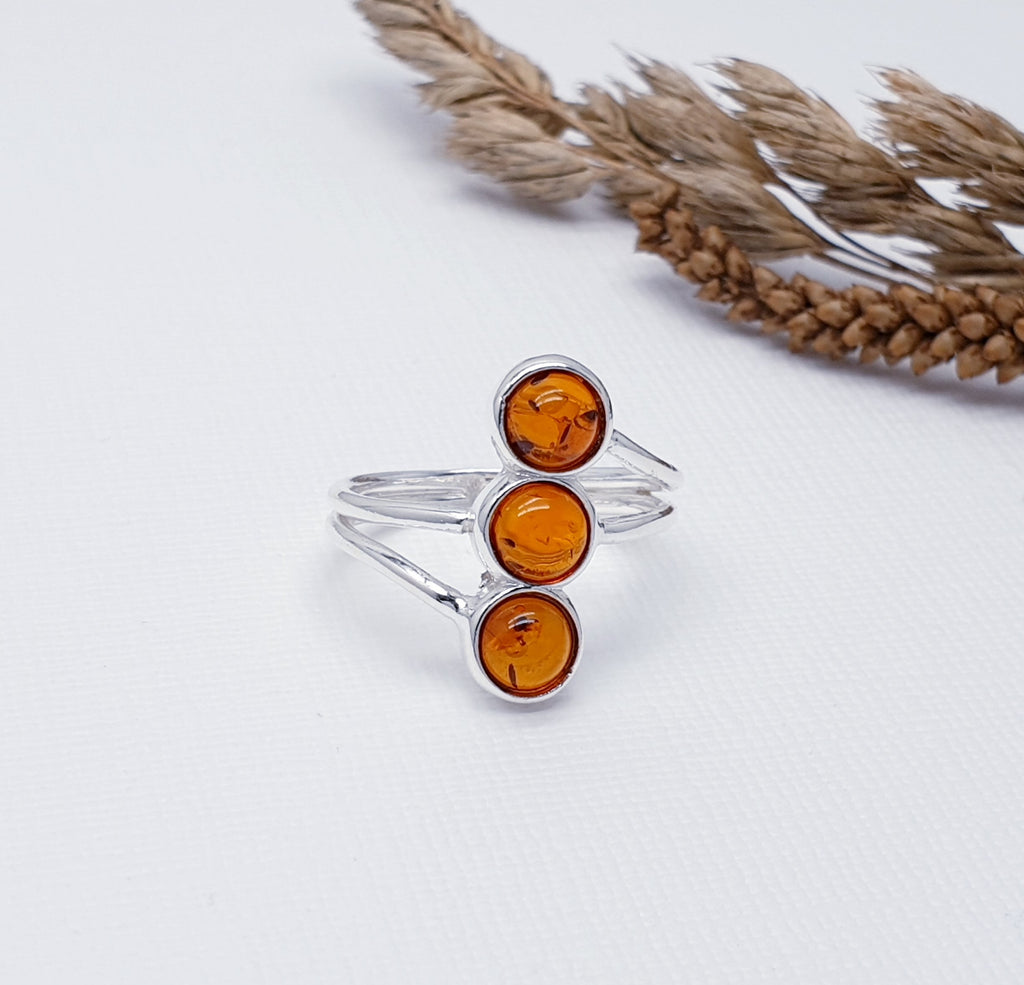 A beautiful design, this ring features a row of three round Toffee Baltic Amber stones in simple settings. Either side of the three stones, two Silver fine wire detailing has been crafted in Silver, giving this ring that 'something a little different' we love so much at Silver Scene.