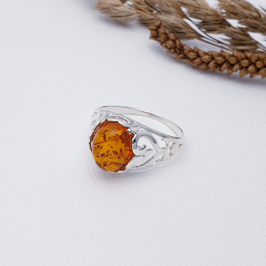 This gorgeous ring features a beautiful oval Toffee Baltic Amber stone. Surrounding the stone is a nature inspired cut out design with a polished finish.