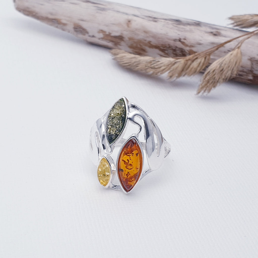 This ring features three marquise shaped Baltic Amber stones; one Toffee, one yellow and one green. The Amber stones are showcased by an abstract Sterling Silver design that decorates each side of the stones.