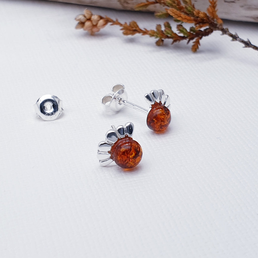 A dainty design, each earring features a round Baltic Toffee Amber stone. The Amber stones are highlighted by a decorative top layer of Silver petals creating a detailed daisy. These earrings will add sparkle and shine to any outfit, you just can't go wrong with this understated pair of studs. 