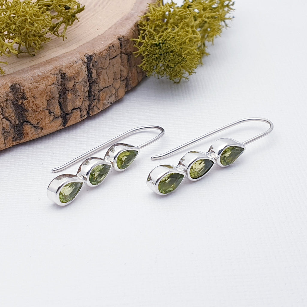An understated design, each earring features three, table top cut, teardrop, Peridot stones in simple Sterling Silver settings. A channel set design with a fixed hook, these little earrings are the perfect complement to any outfit or occasion.
