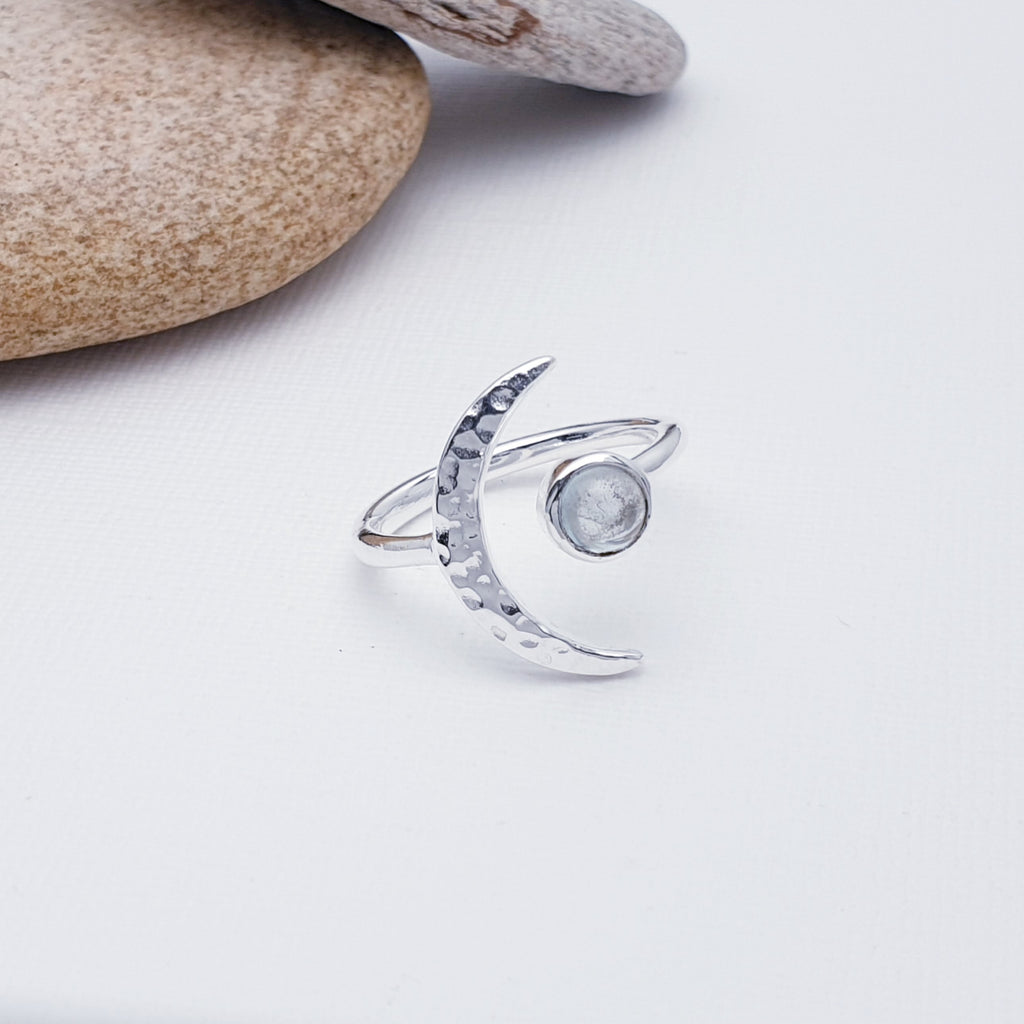 A gorgeous design, this ring features a beautiful cabochon, round Blue Topaz stone in a simple setting. To complement a hammered Sterling Silver crescent moon, wraps comfortably around the finger. 