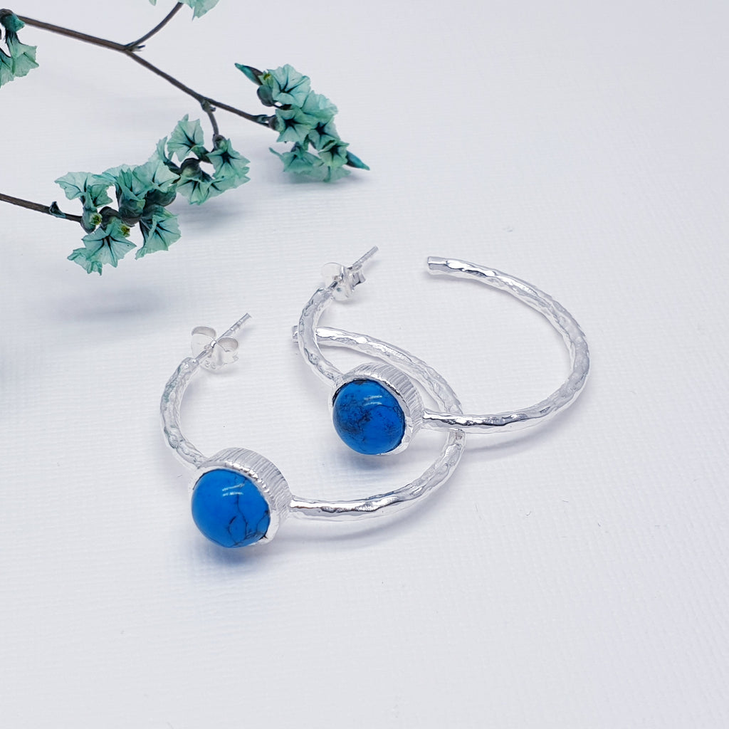 Each earring features a half hoop design with a beautiful, cabochon, Turquoise stone in a Sterling Silver setting. Each hoop has a Sterling Silver hammered effect creating that 'something a little different' we love at Silver Scene. The stud fixing makes these earrings extra secure so you don't need to worry about loosing them.