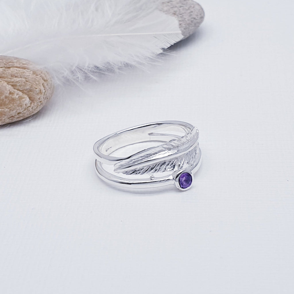 A beautiful design, this ring features a stunning cabochon, round, Amethyst stone in a simple setting. Above the stone is a gorgeous feather, with an 'icing sugar' finish and gorgeous detailing. Two silver bands are fused together at both ends creating an interesting design.