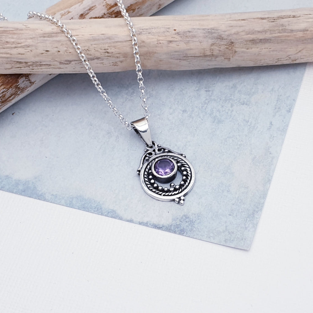 A gorgeous design, this pendant features a round, cabochon Amethyst stone in a simple setting. Intricate Sterling Silver detailing decorates around the stone, and is given depth and presence by the clever use of oxidisation. 