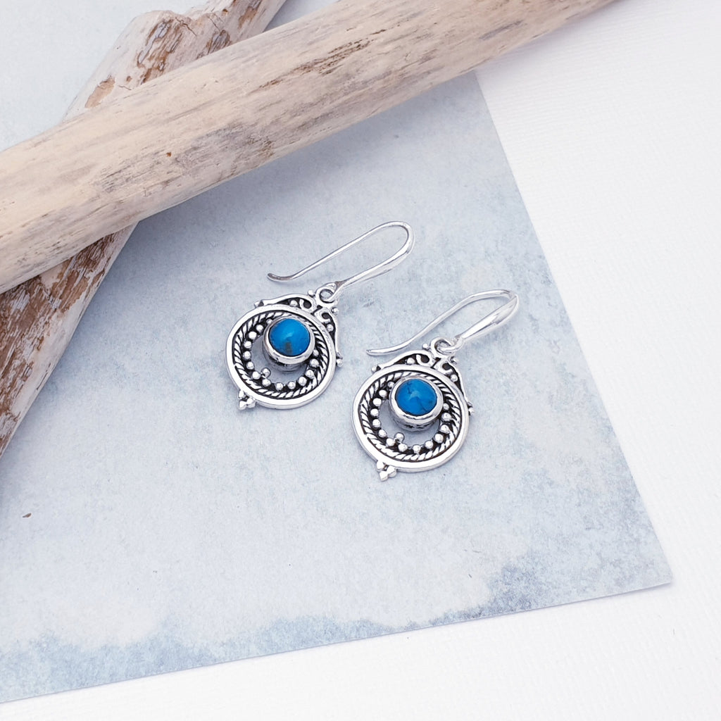 Each earring features a round, cabochon Turquoise stone in a simple setting. Intricate Sterling Silver detailing decorates around the stone, and is given depth and presence by the clever use of oxidisation. 