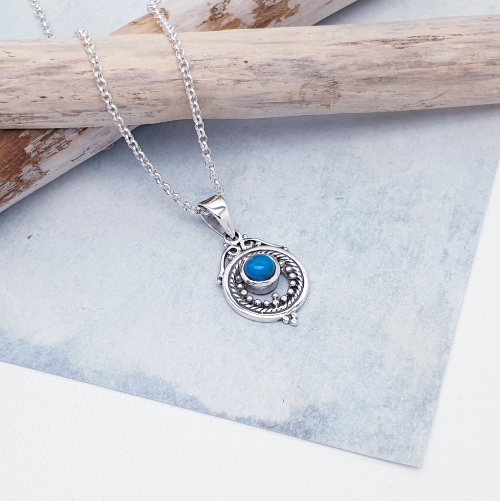 A gorgeous design, this pendant features a round, cabochon Turquoise stone in a simple setting. Intricate Sterling Silver detailing decorates around the stone, and is given depth and presence by the clever use of oxidisation. 