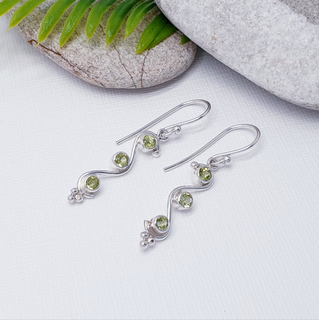 Each earring features three tabletop cut, Peridot stones arranged in a row. An elegant swirl shape design has been crafted in Silver, giving this ring that 'something a little different' we love so much at Silver Scene. To finish off, three Silver balls elegantly decorates the bottom of the earring.