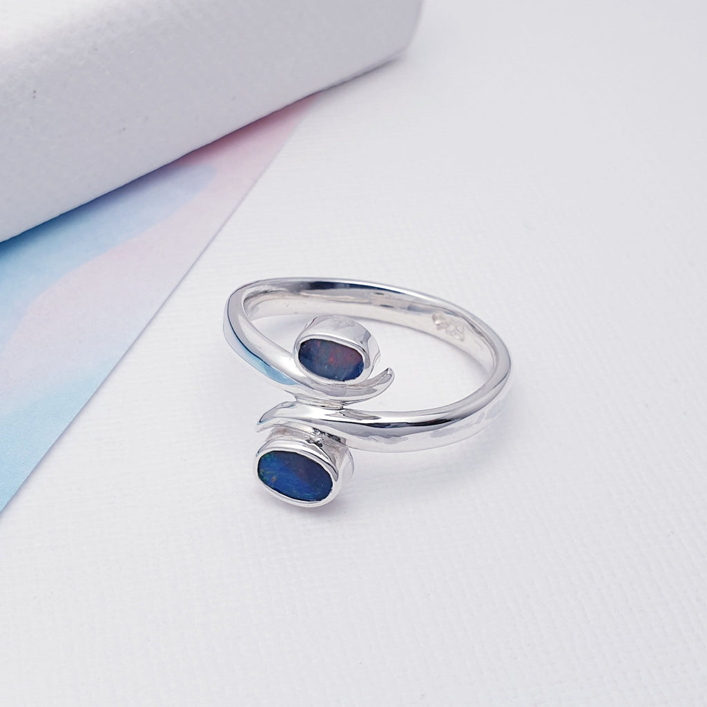 This beautiful ring features two Australian Opal Doublets in Sterling Silver settings. One small around and one larger stone, has been arranged one above the other. The band, gives this ring a wrap around feel, giving it that 'something a little different' we love so much at Silver Scene.