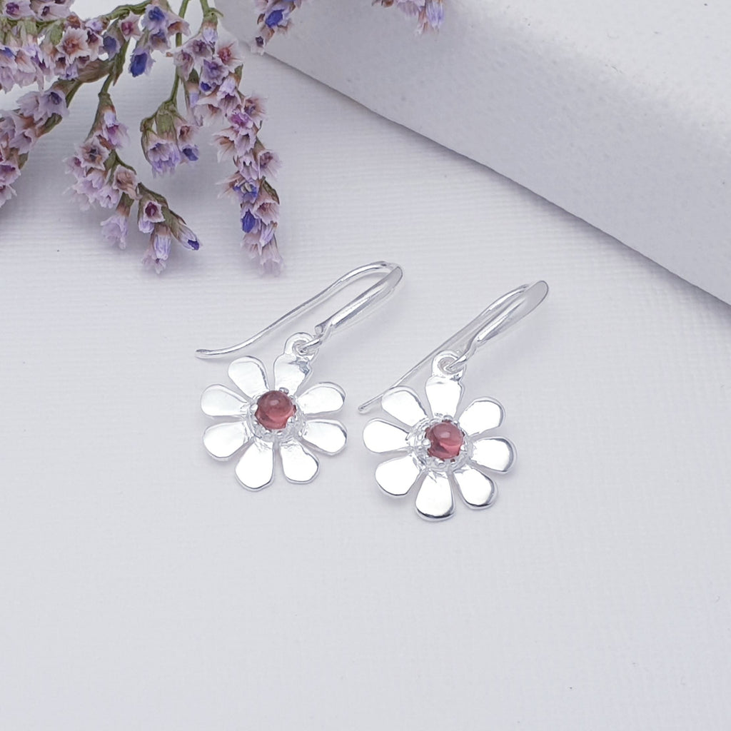 A dainty design, each earring features a round, cabochon Garnet stone. The Garnet stones are highlighted by decorative Silver petals creating a detailed daisy. These earrings will add sparkle and shine to any outfit, you just can't go wrong with this understated pair of studs. 