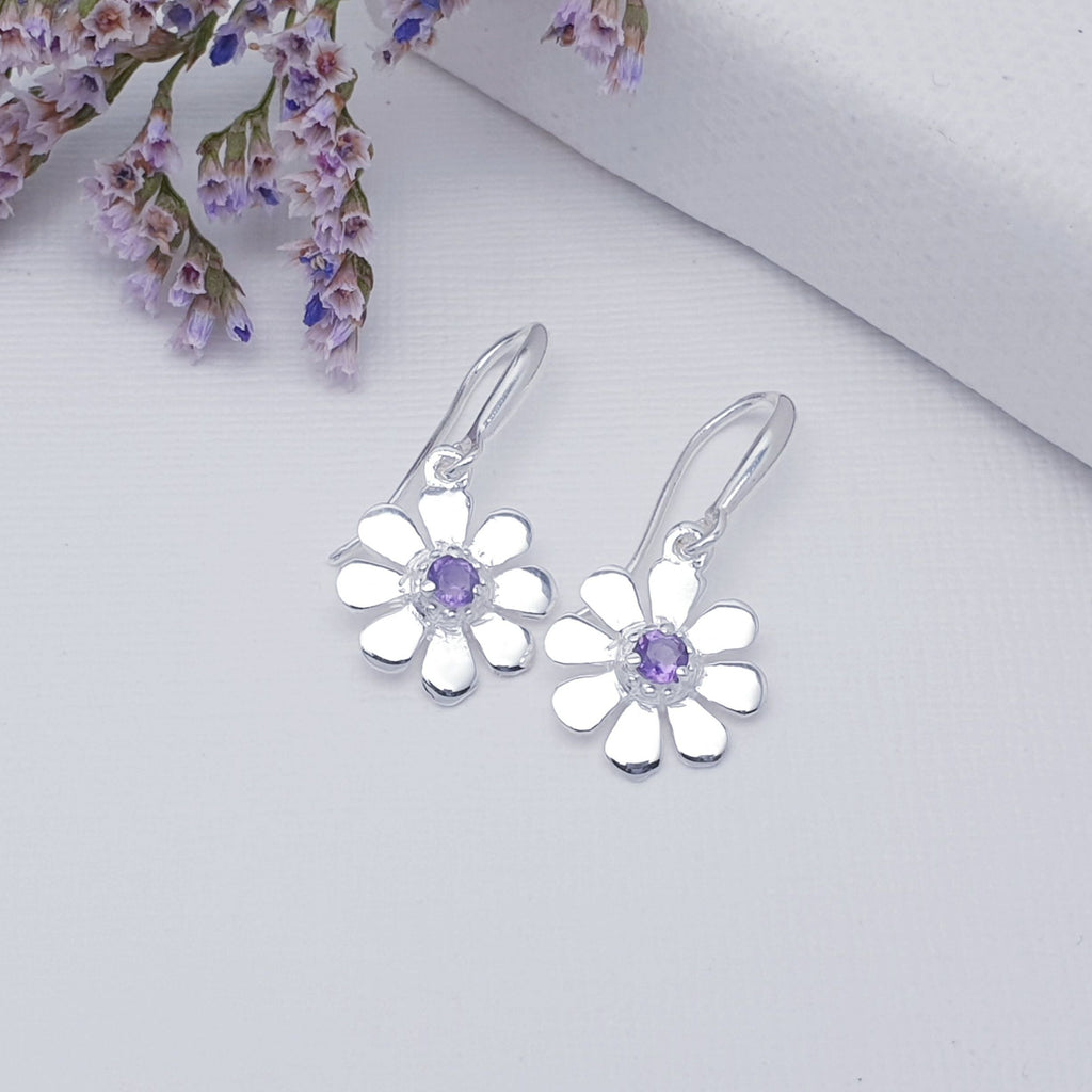 A dainty design, each earring features a round cabochon Amethyst stone. The Amethyst  stones are highlighted by decorative Silver petals creating a detailed daisy. These earrings will add sparkle and shine to any outfit, you just can't go wrong with this understated pair of studs. 