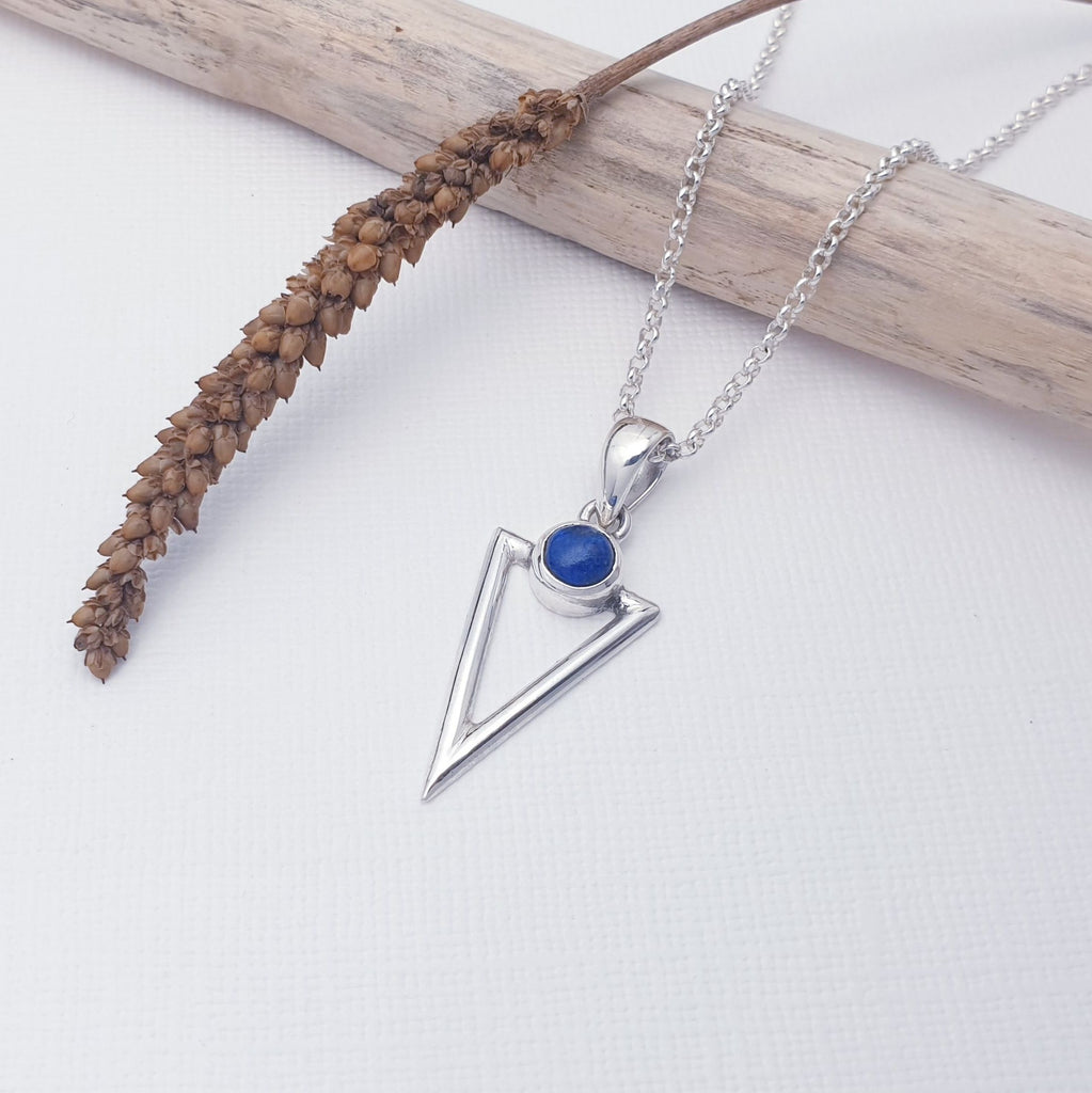 This pendant features a round, cabochon, Lapis Lazuli stone. The stone is set above an acute triangle hand worked in Sterling Silver. A fabulous geometric design, perfect layered with other necklaces creating your own unique look.